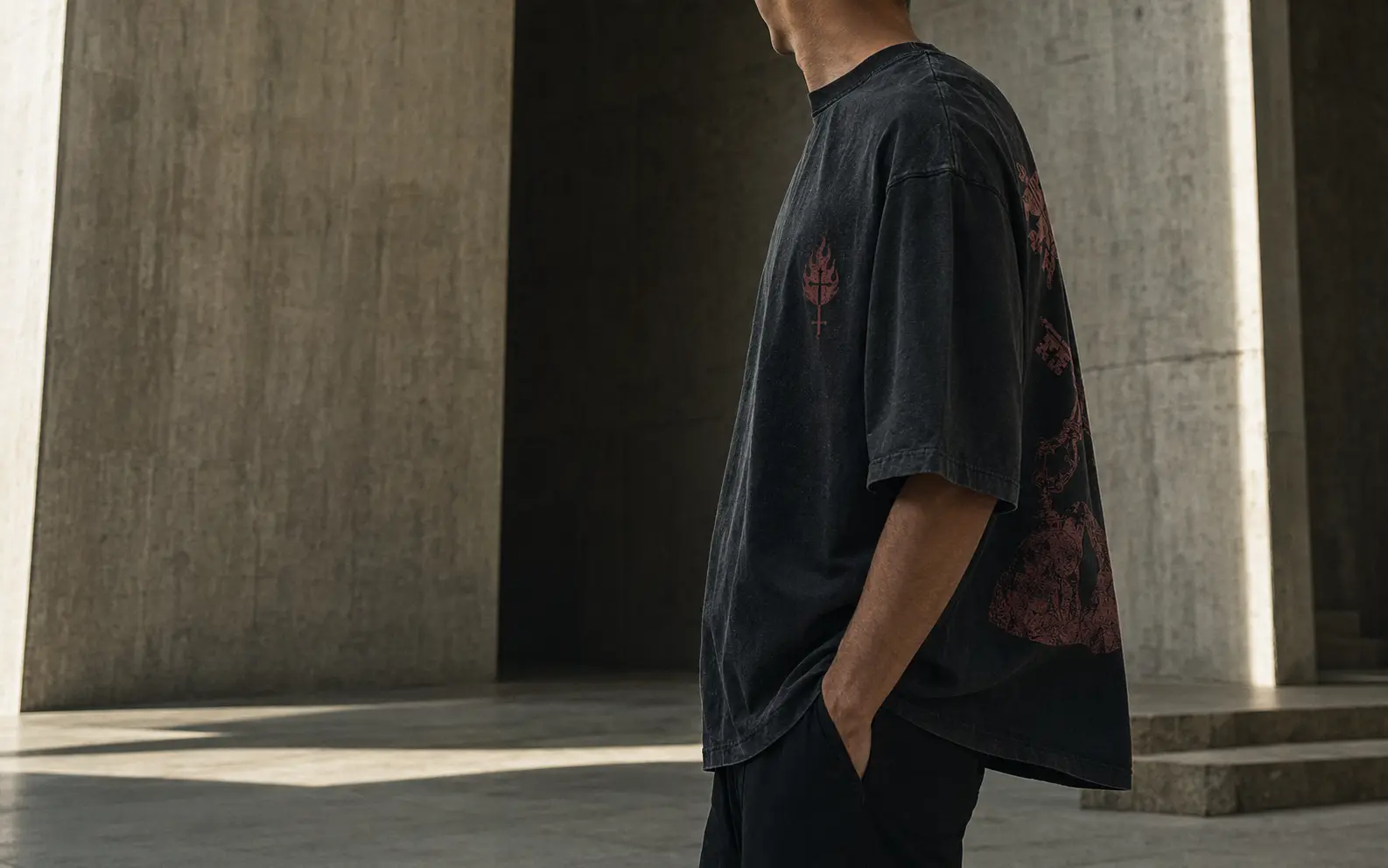 Model wearing a washed-black Votive Thread shirt in a concrete architectural space